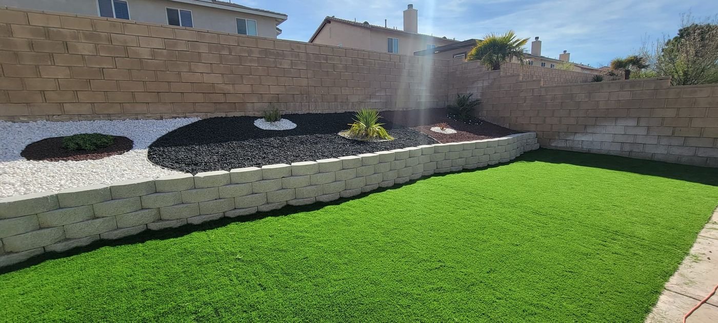 Block retaining wall with rock beds above a turf lawn built by Option 1 Builders