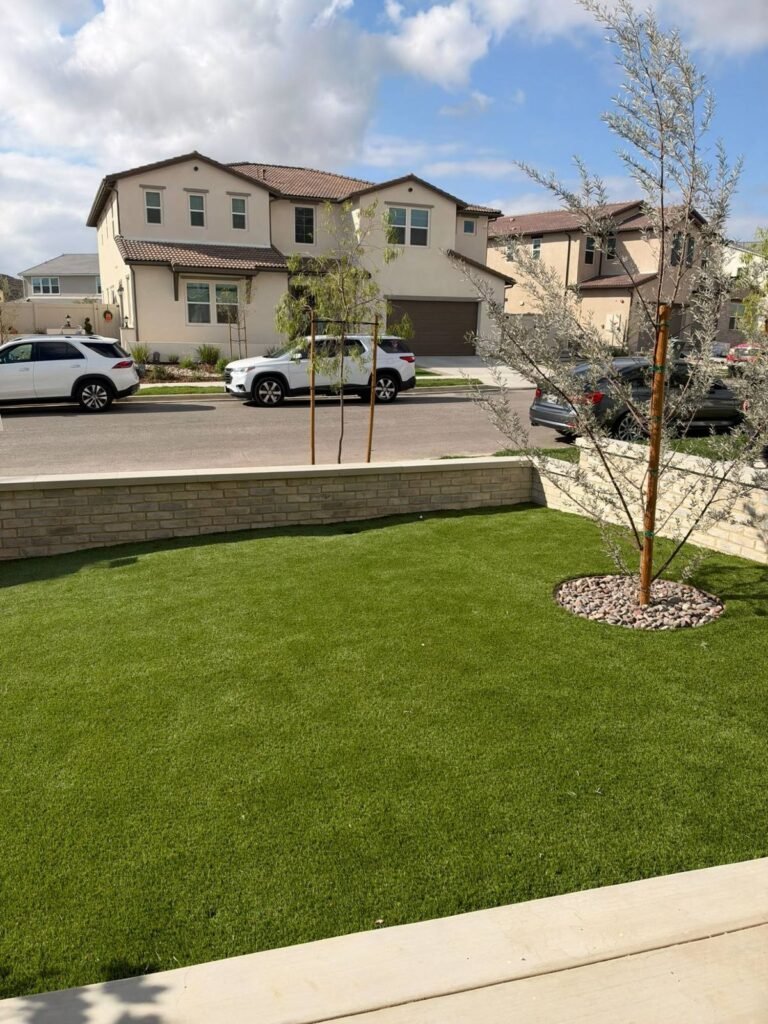 Artificial turf front lawn with a river rock tree ring behind a brick wall in Santa Clarita